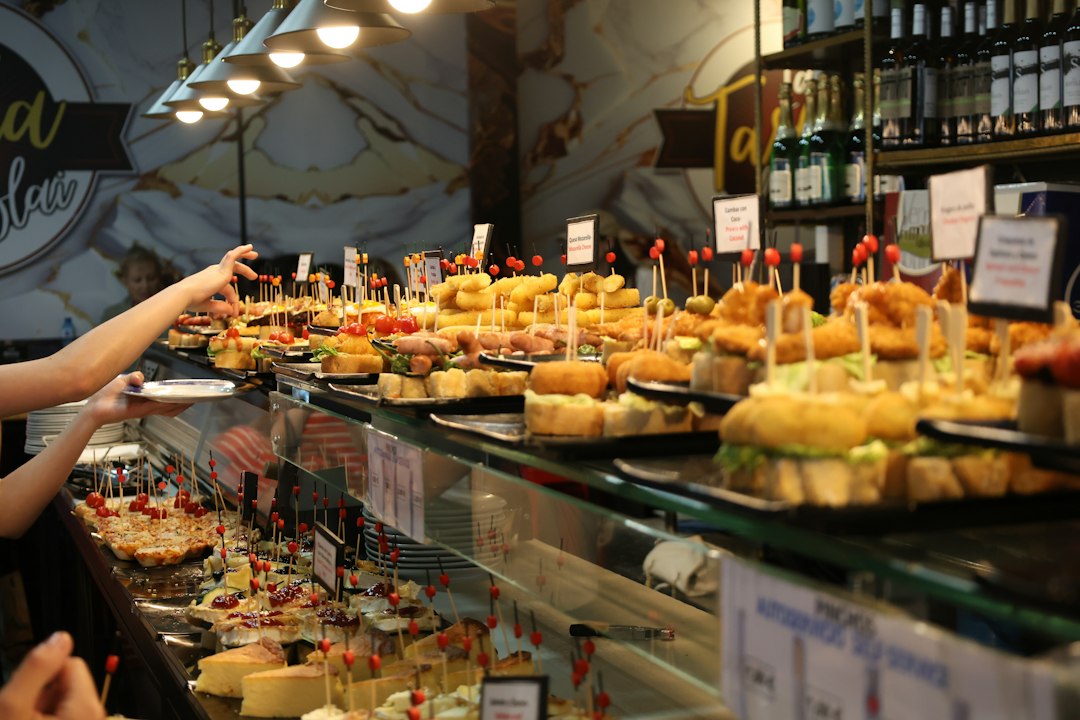 Barra con pintxos variados y una mano cogiendo un plato